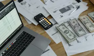 Na ile rat można rozłożyć podatek? Na biurku leży laptop z wykresem, kalkulator, stosy dokumentów i pieniądze.