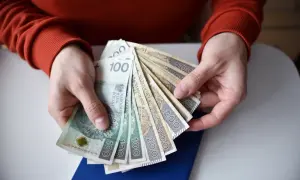 Ręce trzymają polskie banknoty 100 i 200 zł. Zastanawiasz się, ile wynosi renta po świadczeniu rehabilitacyjnym?