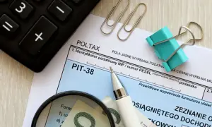 Formularz PIT-38, kalkulator, lupa i pieniądze. Rozliczenie dochodu z art. 27 ust. 9 i 9a ustawy.