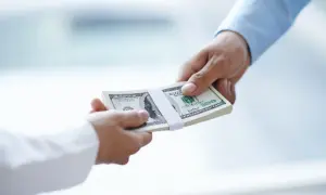 Przekazanie pliku banknotów dolarowych. Zastanawiasz się, do jakiej kwoty można płacić gotówką?