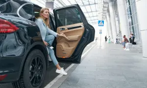 Elegancka kobieta wysiada z luksusowego samochodu, którego proporcja sugeruje wartość powyżej 150 tys. zł.