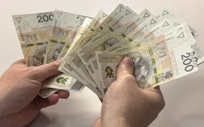 Dłonie trzymają plik banknotów 200 zł. Zastanawiasz się, czy alimenty można odliczyć od podatku?