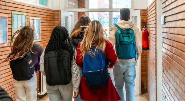 Grupa studentów z plecakami idzie korytarzem. Myślą o przyszłości: status studenta a umowa o pracę.