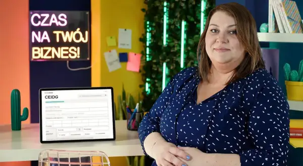 Kobieta w biurze, obok tablet z formularzem CEIDG. Neonowy napis "Czas na Twój Biznes!" sugeruje tematykę zakładania działalności i prawo spółek handlowych.
