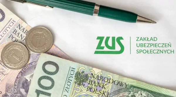 ZUS i polskie złotówki, gotowe do opłacenia składek. Zielony długopis czeka na podpis.