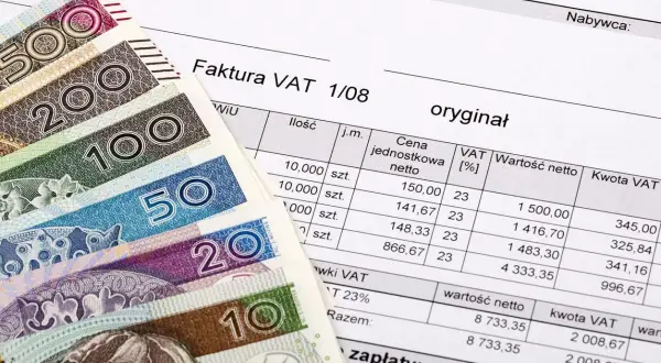 Polskie banknoty i faktura VAT. Dokument finansowy z wyszczególnionymi kwotami netto i VAT.