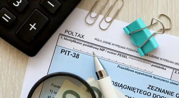 Formularz PIT-38, kalkulator, lupa i pieniądze. Rozliczenie dochodu z art. 27 ust. 9 i 9a ustawy.