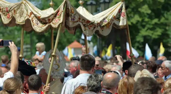 Procesja Bożego Ciała. Czy to dzień wolny od pracy? Ludzie obserwują, niektórzy filmują telefonami.
