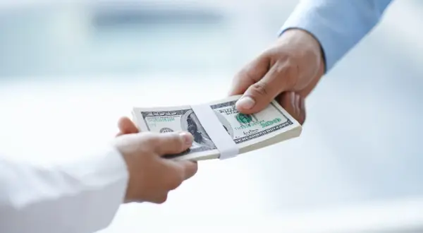Przekazanie pliku banknotów dolarowych. Zastanawiasz się, do jakiej kwoty można płacić gotówką?