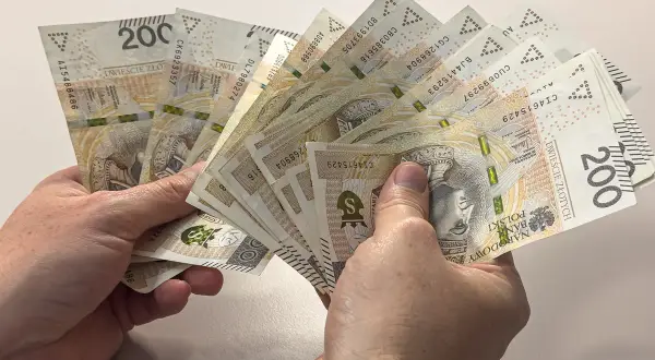 Dłonie trzymają plik banknotów 200 zł. Zastanawiasz się, czy alimenty można odliczyć od podatku?