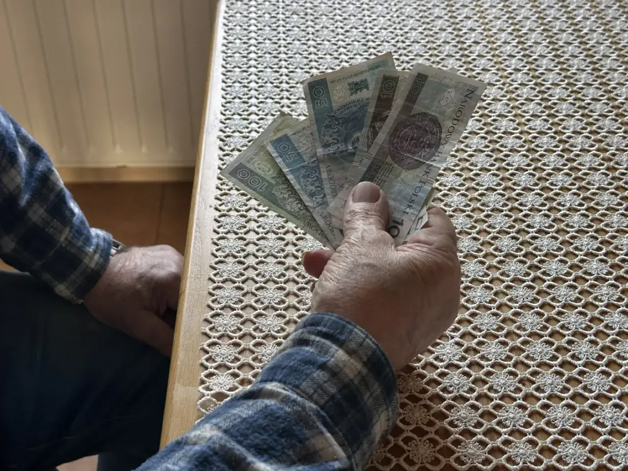 Dłoń trzyma banknoty. Czy to zapowiedź wyższego wskaźnika waloryzacji emerytur 2026?