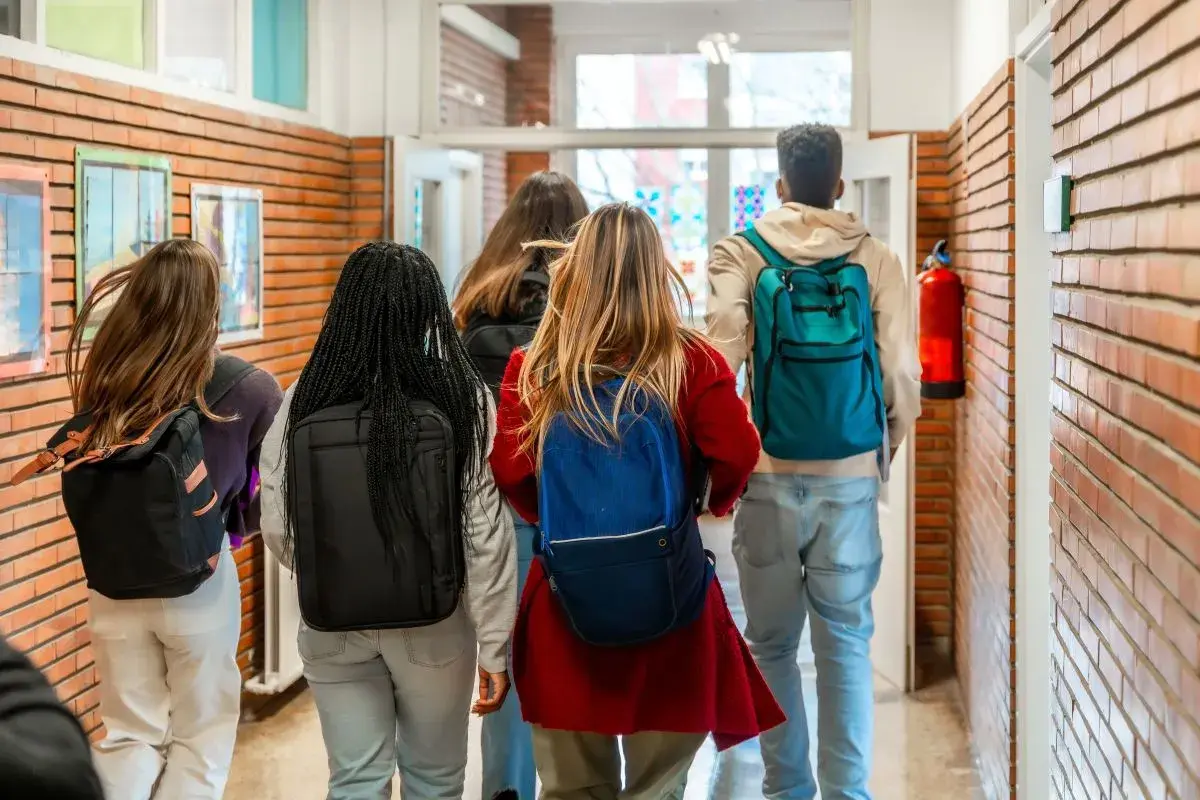 Grupa studentów z plecakami idzie korytarzem. Myślą o przyszłości: status studenta a umowa o pracę.