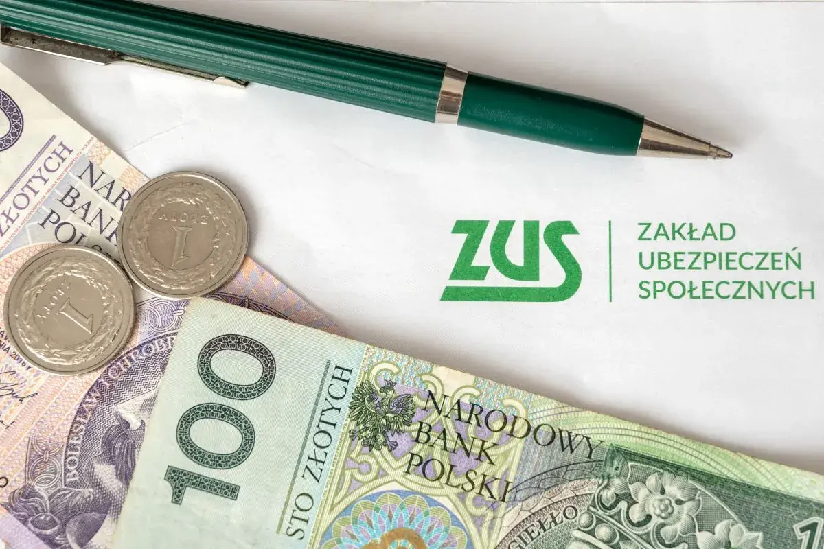 ZUS i polskie złotówki, gotowe do opłacenia składek. Zielony długopis czeka na podpis.
