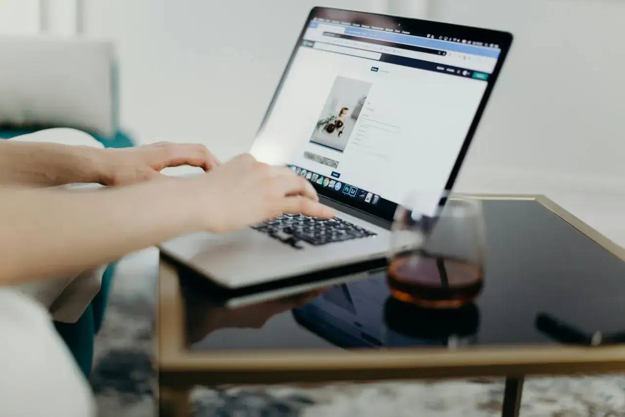 Dłonie piszą na laptopie, tworząc nowe projekty. To praca poza miejscem zamieszkania, w komfortowych warunkach.