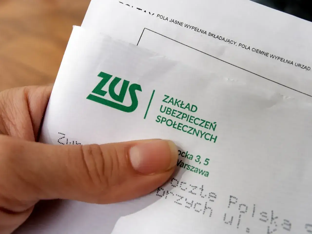 Dłoń trzyma dokument ZUS. To ważny krok w kierunku odprawy emerytalnej, gdzie składki ZUS odgrywają kluczową rolę.