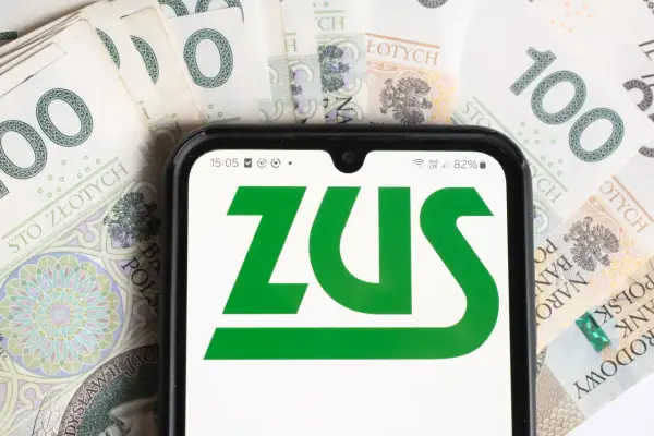 Pierwsza wypłata emerytury po raz pierwszy! Na ekranie telefonu logo ZUS, a w tle polskie stuzłotówki.
