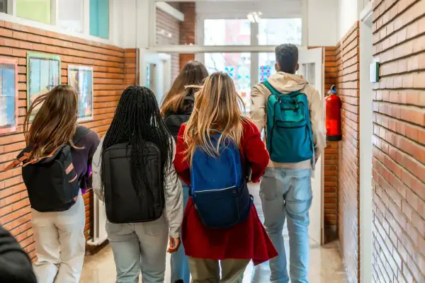 Grupa studentów z plecakami idzie korytarzem. Myślą o przyszłości: status studenta a umowa o pracę.