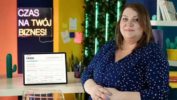 Kobieta w biurze, obok tablet z formularzem CEIDG. Neonowy napis "Czas na Twój Biznes!" sugeruje tematykę zakładania działalności i prawo spółek handlowych.