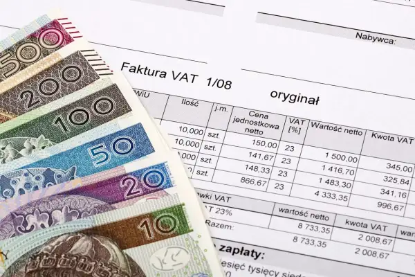 Polskie banknoty i faktura VAT. Dokument finansowy z wyszczególnionymi kwotami netto i VAT.