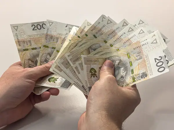 Dłonie trzymają plik banknotów 200 zł. Zastanawiasz się, czy alimenty można odliczyć od podatku?